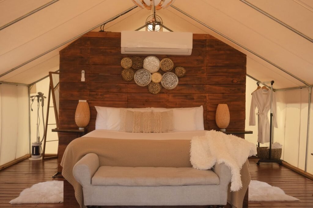 Elegant glamping tent featuring a beautifully designed bedroom with cozy textiles and rustic decor.